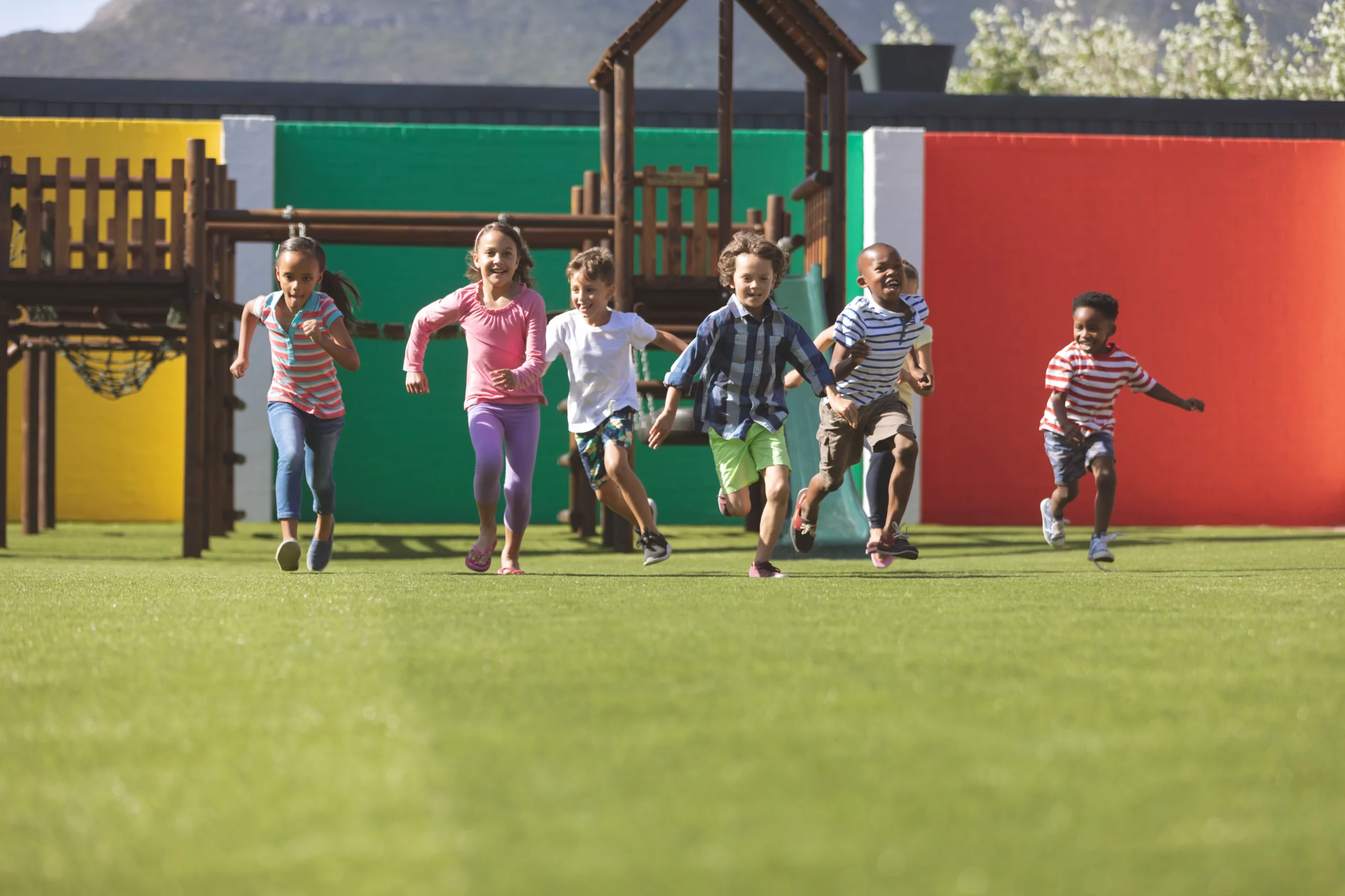 Six children running across a colorful playground, highlighting daycare safety concerns.